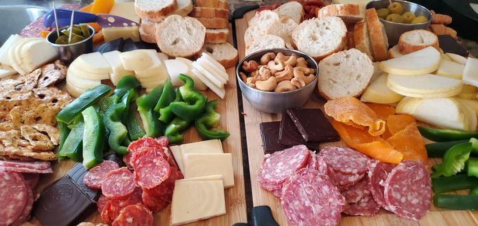 A charcuterie board filled with deli meat, fruit, vegetables, bread, crackers and cheese