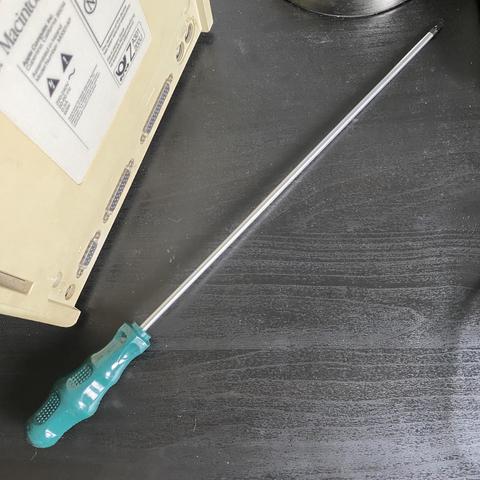 A T15 long torx screwdriver next to the back of a Mac Plus