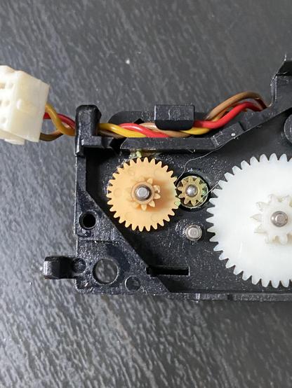 The eject mechanism open. A gear with missing teeth can be clearly seen.