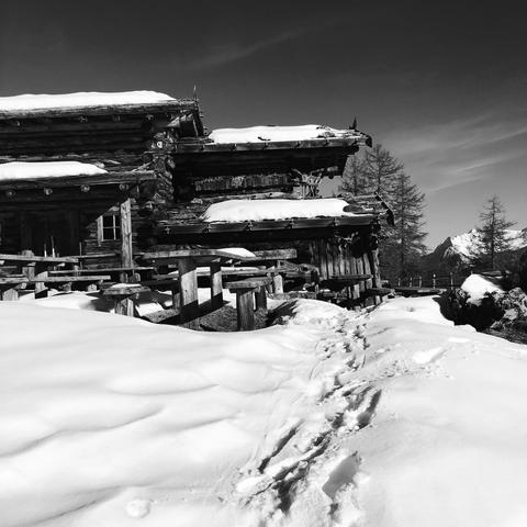 Tracce nella neve e la malga con il tetto coperto di neve