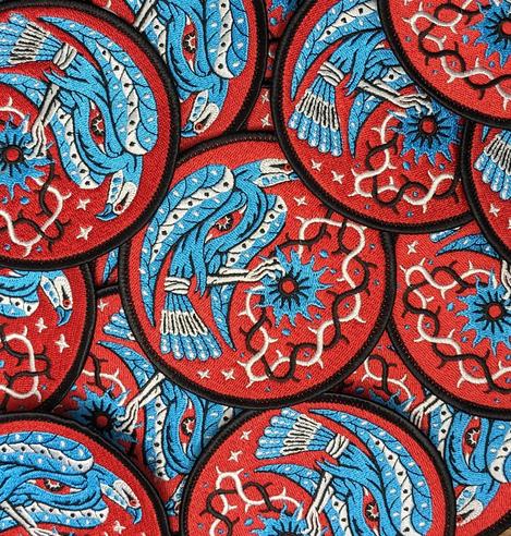 Patch brodé en rouge noir bleu représentant un oiseau.