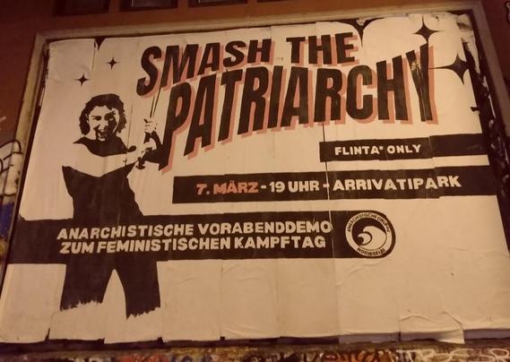 Auf der Plakatwand der roten Flora ist ein Aufruf zu sehen:
Smash the Patriarchy in schwarzer Schrift mit rotem Schatten. Links daneben eine weiblich gelesene Person mit erhobenem Schwert oder Schlagstock in schwarz weiß.
Weiter in weiß mit schwarem Hintergrund FLINTA* only und 7. März (in rot) - 19 Uhr - Arrivatipar und weiter
anarchistische Vorabenddemo zum feministisch|en Kampftag. Daneben Logo der anarchistischen Gruppe Norderelbe.
Im oberen Teil noch Sterne.
