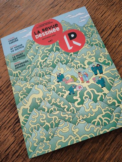 photo of the cover of the french magazine Revue Dessinée issue 47 of spring 2025 with the following titles: nature - private hunting ground, Guyana - and vogue justice, Thiaroye 1944 - death as a bonus, prison - locked outside.  as well as an illustration of Laura lion. which depicts hikers on paths that are blocked by various characters.