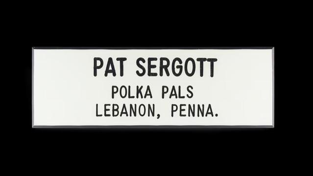 Name tag with text: Pat Segott, Polka Pals, Lebanon, Penna. (Black text on a plane white background, engraved in the Gordon font with its characteristic straight lines and rounded ends. Like a boring, mechanized Comic Sans.