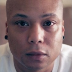 Photo of Leon Lamont, an African-American man looking forward with gentle eyes, shaved head, wearing a white t-shirt. 