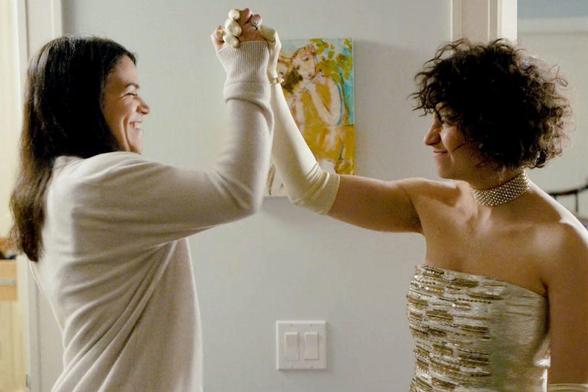 Broad City's Abbi and Ilana high fiving and smiling broadly.