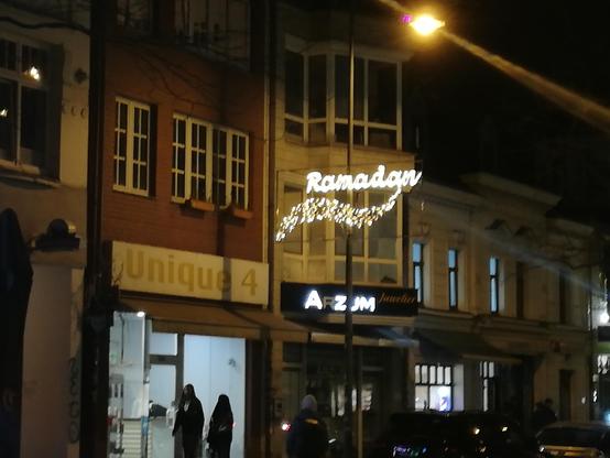 Goldene Leuchtdekoration über einer Einkaufsstraße mit dem Schriftzug "Ramadan" 
