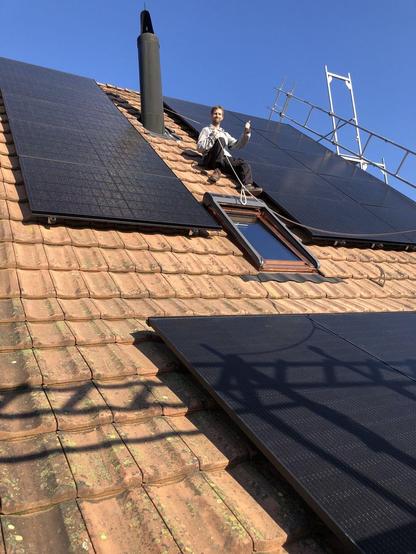 Steiles Hausdach mit neuer Solaranlage und winkendem Solarteur