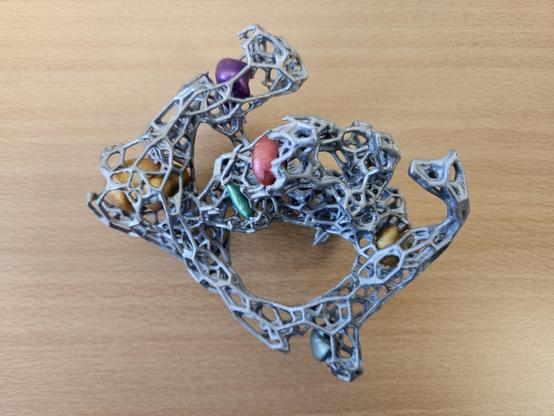 A photography of a tactile model of the Cosmic Web, that is, the large scale structure of the Universe. It features a materialization of the Cosmic Web filaments, by means of a grey mesh, and a materialization of Cosmic Web knots, by means of filled, colored blobs. Such knots include: the Great Attractor, Perseus-Pisces, Shapley, Hercules, Norma. The location of our Home galaxy the Milky Way is at the center of the model.