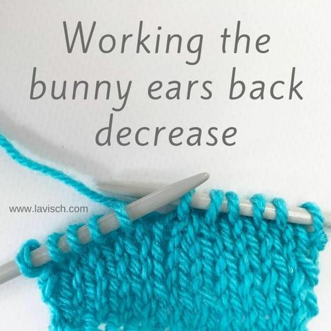 A swatch in turquoise yarn on gray knitting needles, in which the bunny ears back decrease is shown.