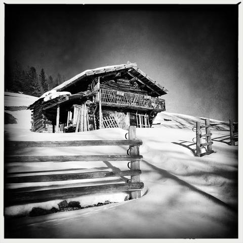 Un prato innevato con uno steccato ed una casetta in legno