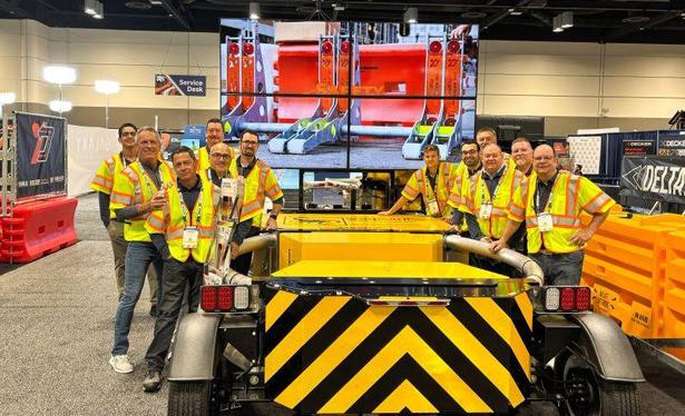 The TrafFix Devices Sales & Marketing team standing around the Scorpion Towable Attenuator with a 4 tv display showing the BlockAxess hostile vehicle mitigation system in front of the Water-Wall.