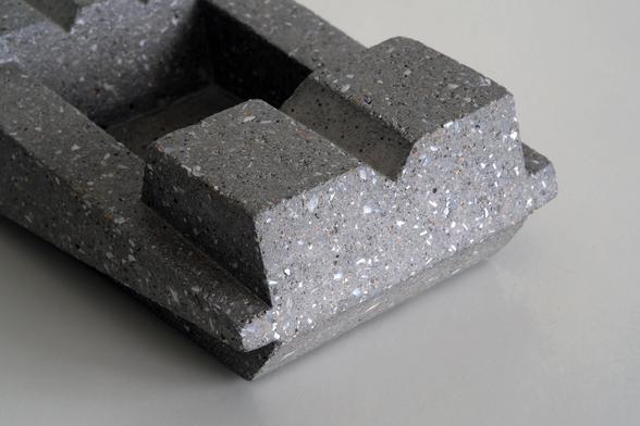 Close up shot from an abstract geometric shaped ashtray. The ashtray is from concrete and is sanded down so specs of crushed shells and river sand appear on the surface resulting in a Terrazzo finish.