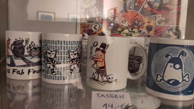 Tassen mit Comic-Motiven des Künstlers Rauti in einer Vitrine!
