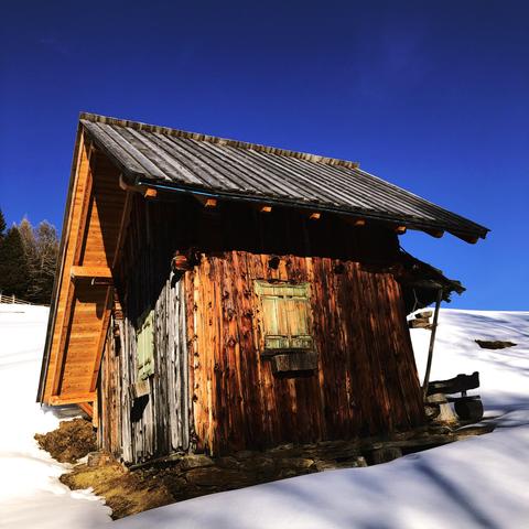 Una piccola casetta in legno su di un prato ricoperto di neve