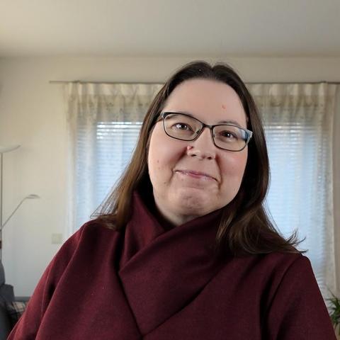 A woman in a red sweater with large shawl collar smiling into the camera.