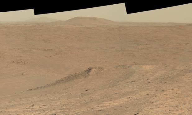 An ochre toned picture of a Martian landscape of hills and dunes.
