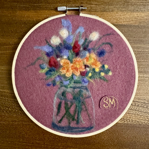 Colourful needle felted bouquet on plum background, framed in embroidery hoop.