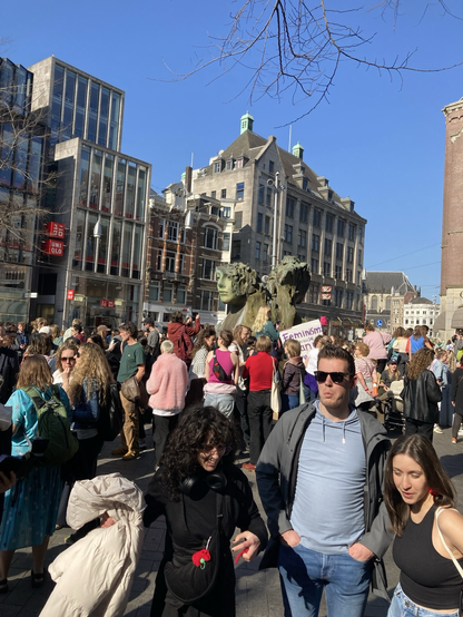 Photo of a crowd in Amsterdam. Some people are holding signs.