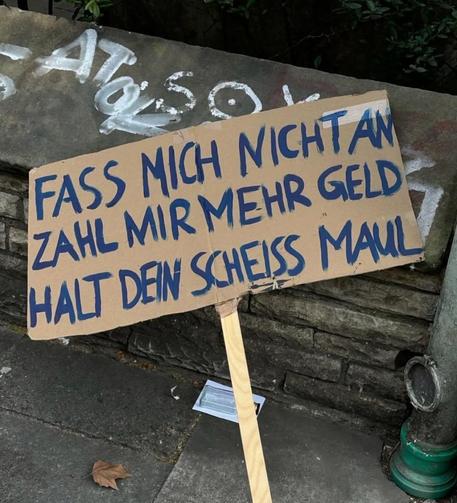 Demo-Schild mit den Worten:
Fass mich nicht an
Zahl mir mehr Geld 
Halt Dein scheiß Maul