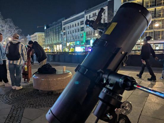 Leute blicken durch ein Dobson-Teleskop. Im Vordergrund ist ein Teleskop auf äquatorialer Montierung.