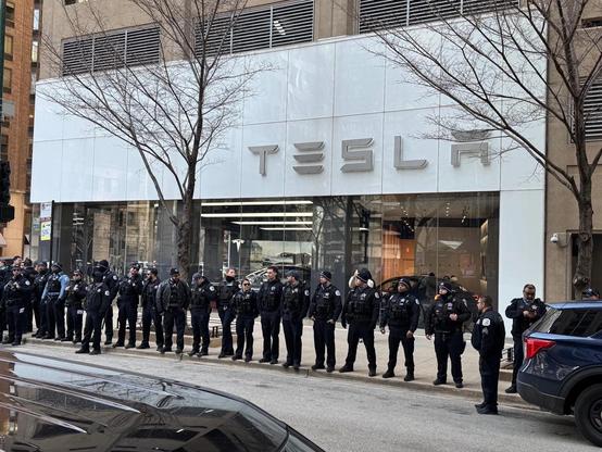 Image of dozens of police lining up to protect a Tesla dealership.