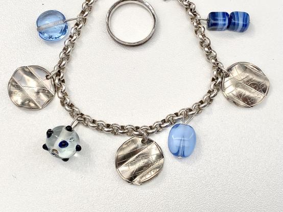 Silver bracelet with glass beads and ‘kwartjes’ as charm. 
