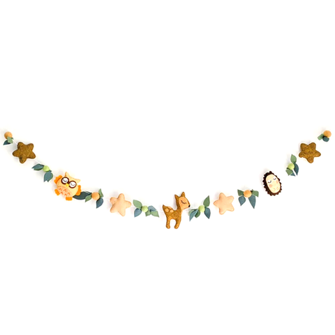 Guirlande en feutrine de laine fait-main par l'atelier jocha. Elle présente un hibou, une biche, un hérisson, des étoiles, des boules de laine et du feuillage dans des tons naturels.
