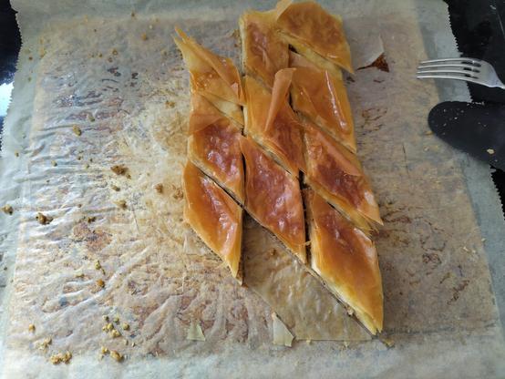 Quelques baklavas posés sur du papier sulfurisé sur une plaque de cuisson. Il y avait visiblement bien plus de baklavas quand ils sont sortis du four !
