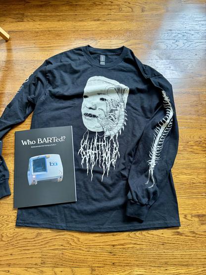 A longsleeve black shirt with heavy metal artwork and writing on it. It says "Chat Pile" in a heavy metal font, and has two long centipedes printed on the arms. There's also a magazine called "Who BARTed?" which is a indie zine about BART and mass transit. 