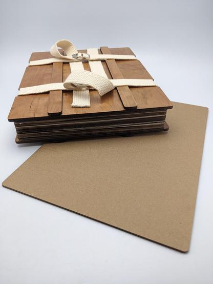 Laser cut, international paper size compatible herbarium flour press with one of it's laser cut pieces of cardboard below it.