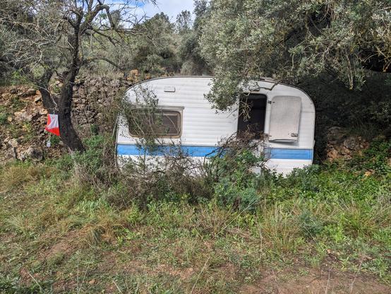 An orienteering control point next to an abandoned caravan
