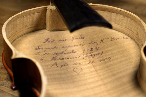 L'intérieur d'un violon avec un message écrit à la plume par le jeune luthier qui l'a fabriqué en 1885.