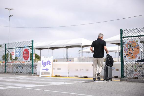 A man crossing a street in the cross-walk heading to the rideshare pickup and drop off location at the LAX airport.
