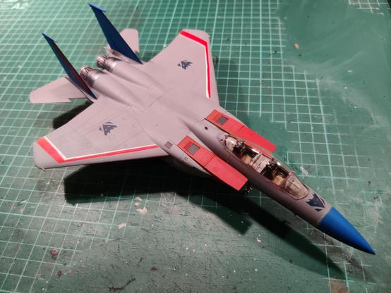 A 1:72 scale model of an F-15E jet painted to look like Starscream, the Transformer. The model is placed on a green, well-worn cutting mat and it is seen from a 3rd person front-right viewpoint. The Decepticon insignia are purplish and not exactly as detailed as the source material dictates.