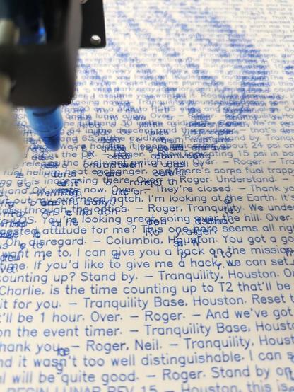 A pen plotter writing text from the Apollo 11 moon landing transcript. Parts of the text are darker from several layers overlapping, and zooming out reveals the iconic Armstrong foot print.