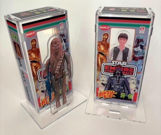 Photo de deux boîtes acryliques et de leurs personnages. Il s'agit à gauche de #Chewbacca et à droite de #HanSolo
Sur les boîtes à l'image de l'Empire Contre-Attaque, il y a C-3PO à gauche et Boba Fett à droite, au centre en bas, il y a #DarkVador #DarthVader.
