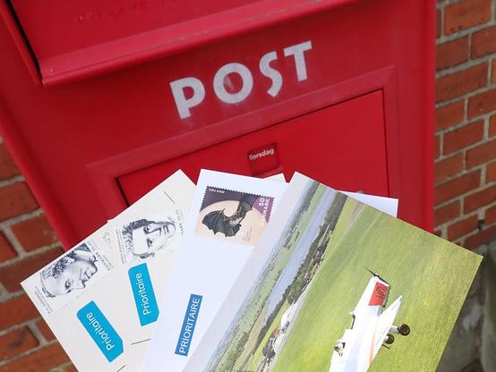 4 postcards and letters with postage about to be put in a very worn mailbox.