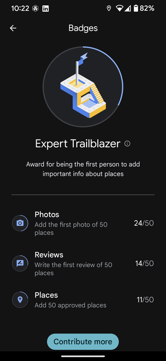 The image is a screenshot of a Google Maps mobile app screen for the Expert Trailblazer badge. The app has a black background with a blue circle in the center. Inside the circle, there is an illustration of a trailblazer with a yellow and blue color scheme. Below the illustration, there are three score wheels; "Photos 24/50", "Reviews 14/50", and "Places 11/50". 

Below that, it reads "Award for being the first person to add important info about places". On the bottom left corner, there has a button that says "Contribute more".

The overall design of the app is simple and modern, with a clean and minimalistic layout.