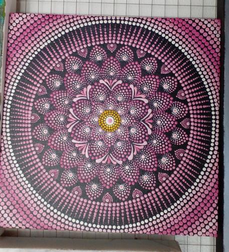 a pink and white mandala on black with a golden ring in the center 