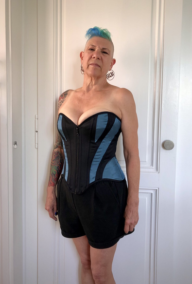 Personne portant un corset, qui est une création sur mesure, noir avec des empiècements turquoises