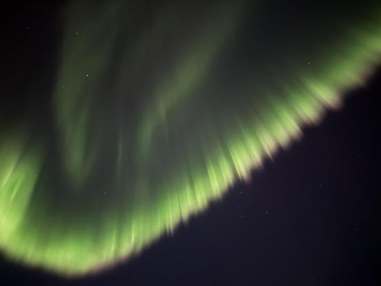 A curtain of green aurora with some red at the bottom