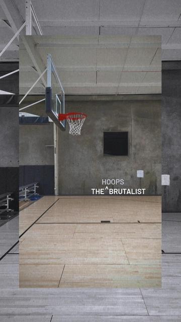 Photo of an indoor basketball hoop against a textured concrete wall backdrop.