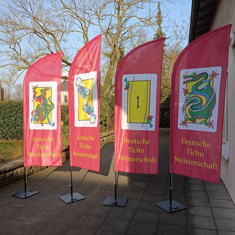 Vier Ständer mit Flaggen, die die Sonderkarten des Spiels Tichu zeigen.