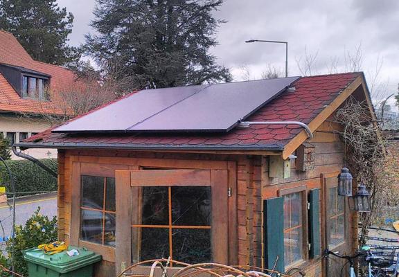 Gartenhäus mit zwei Solarmodulen auf dem Dach.
