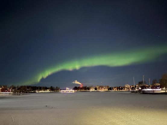 A green wave of northern lights over the frozen bay of Oulu