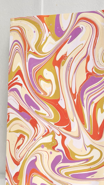 Schwungvolles marmoriertes Muster auf Papier aus lila, gelb und orange.