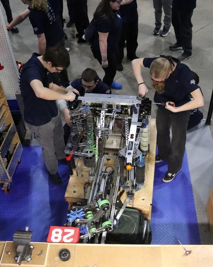 A top-down photo of students working on the Stormbots robot in their pit.