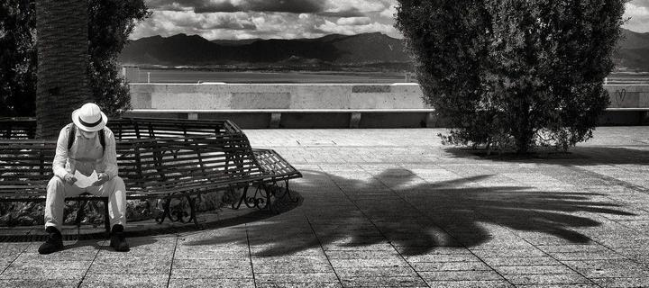 the reminder: a black-and-white photograph of a man sitting on a bench and reading a letter