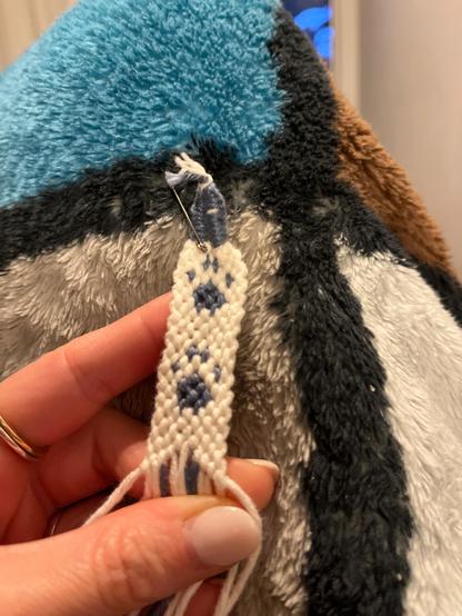 A friendship bracelet in white with blue paws on it.